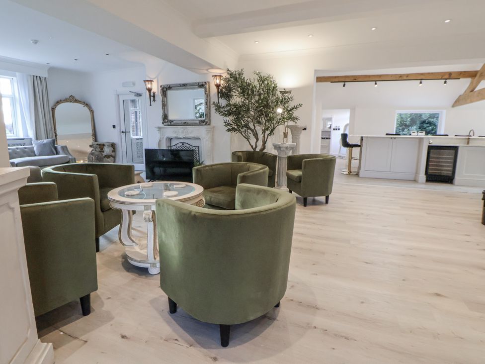 A living room with green chairs and a table at The House at School Farm in Hassall near Haslington