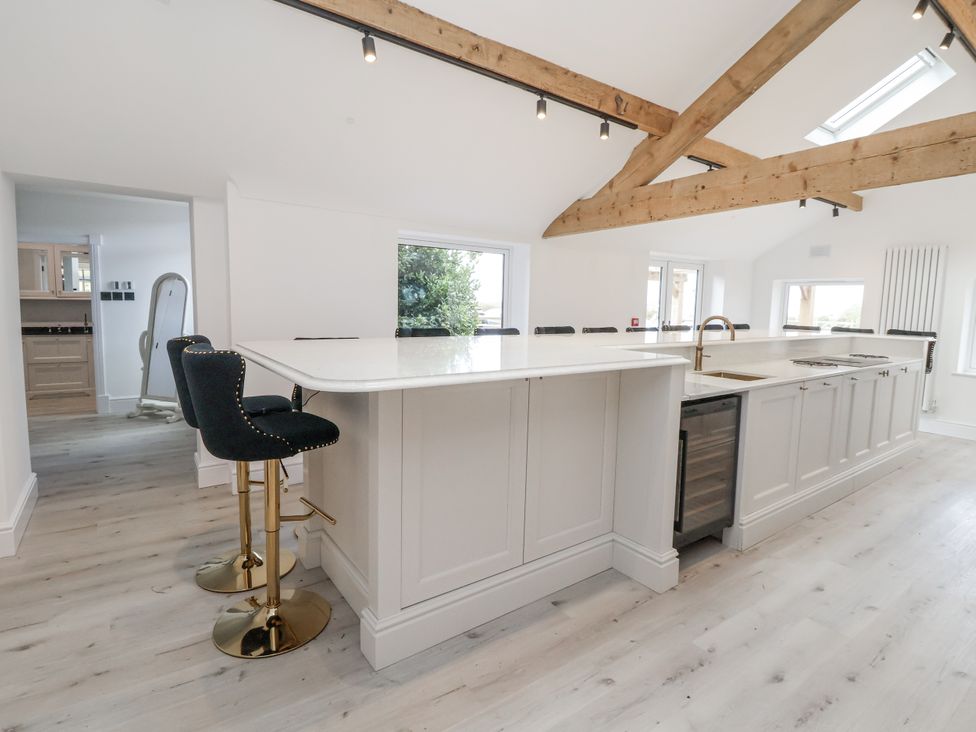 A kitchen with an island and bar stools at The House at School Farm in Hassall near Haslington