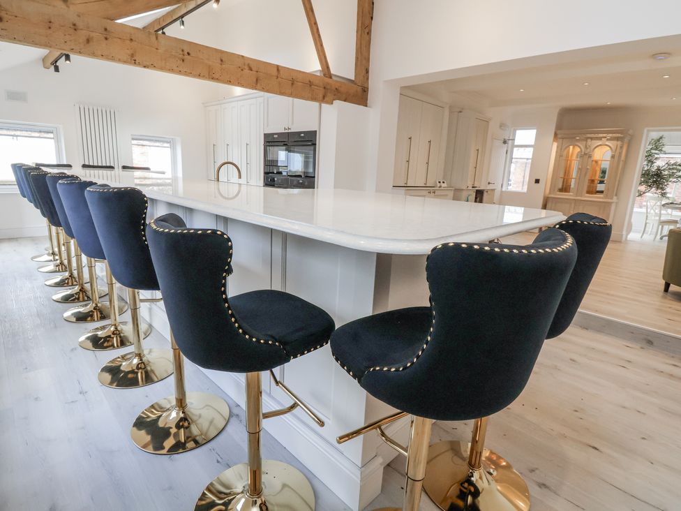 A kitchen with bar stools in front of a countertop at The House at School Farm in Hassall near Haslington