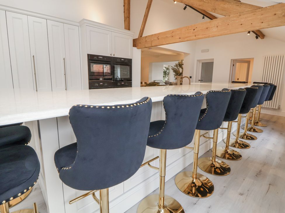 A kitchen with bar stools and cabinets at The House at School Farm in Hassall near Haslington