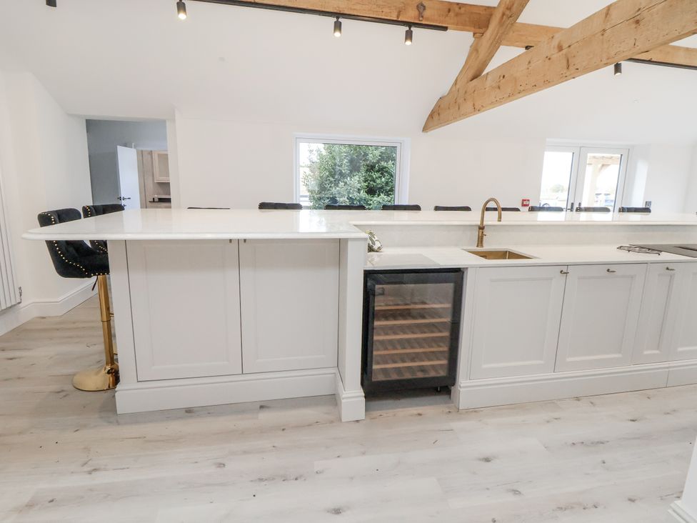 A kitchen with an island, sink, and wine cooler at The House at School Farm in Hassall near Haslington