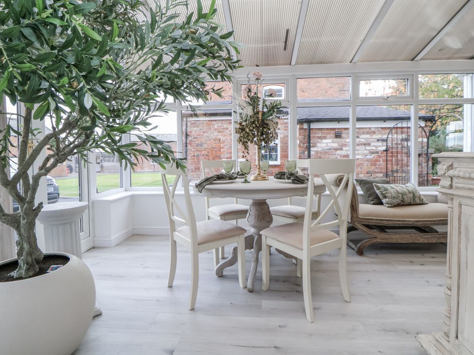 A conservatory with a table and chairs at The House at School Farm in Hassall near Haslington