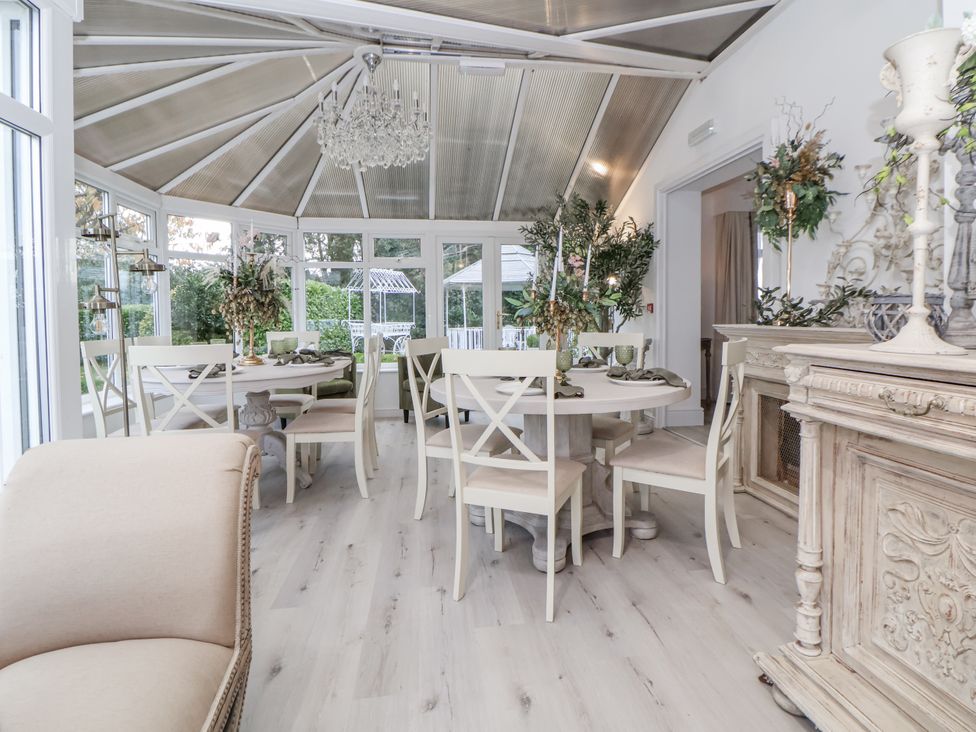A conservatory with dining table and chairs at The House at School Farm in Hassall near Haslington