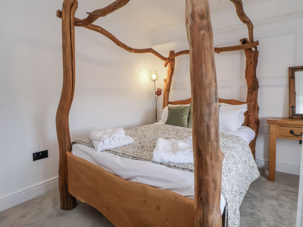 A bedroom with a wooden bed and lamp at The House at School Farm in Hassall near Haslington