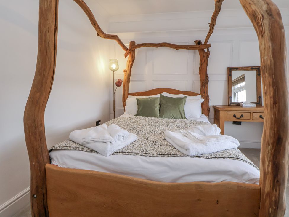 A bedroom with a wooden bed and bedside lamp at The House at School Farm in Hassall near Haslington
