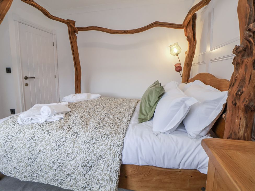 A bedroom with a wooden bed and linens at The House at School Farm in Hassall near Haslington