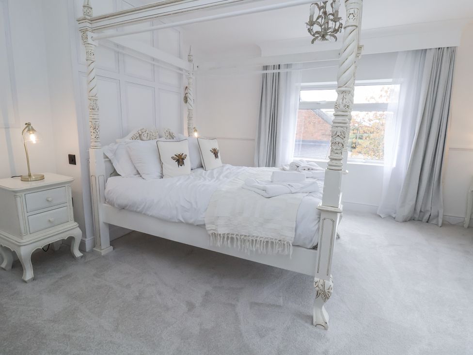 A bedroom with a four-poster bed and bedside table at The House at School Farm in Hassall near Haslington