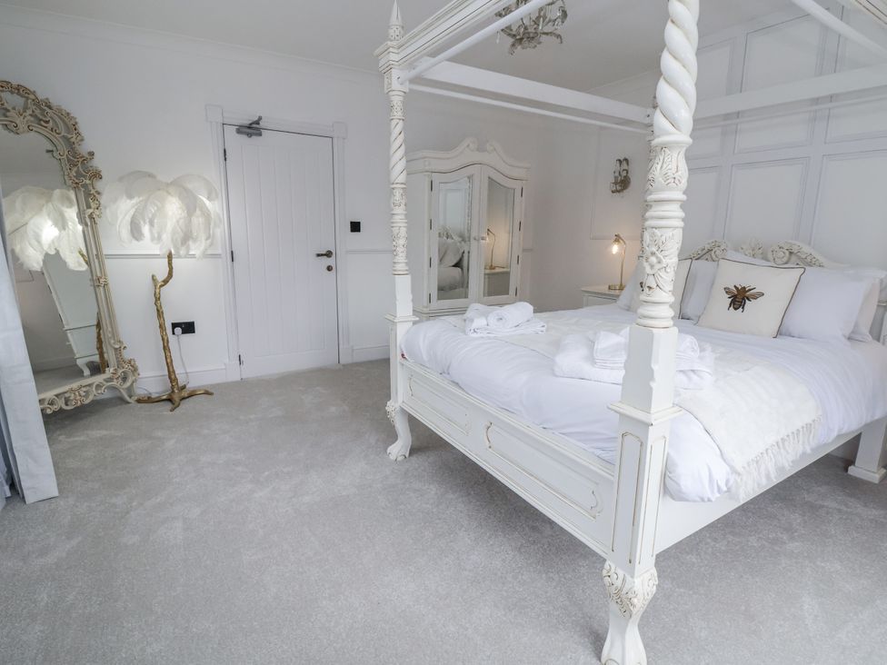 A bedroom with a four-poster bed and a decorative mirror at The House at School Farm in Hassall near Haslington