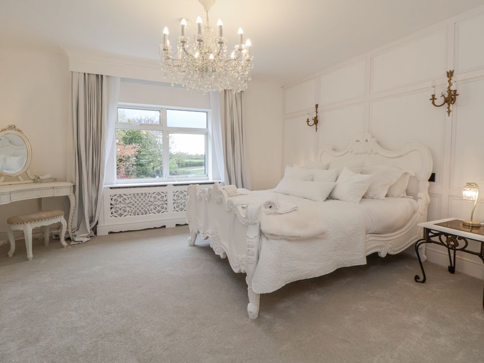 A bedroom with a bed and chandelier at The House at School Farm in Hassall near Haslington