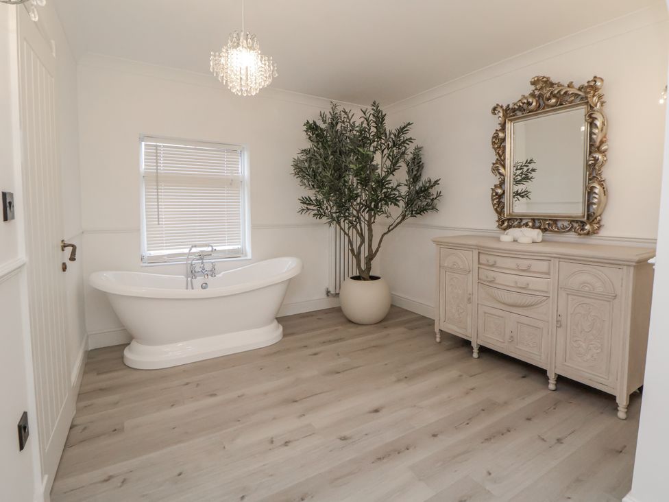 A bathroom with a bathtub and a cabinet at The House at School Farm in Hassall near Haslington