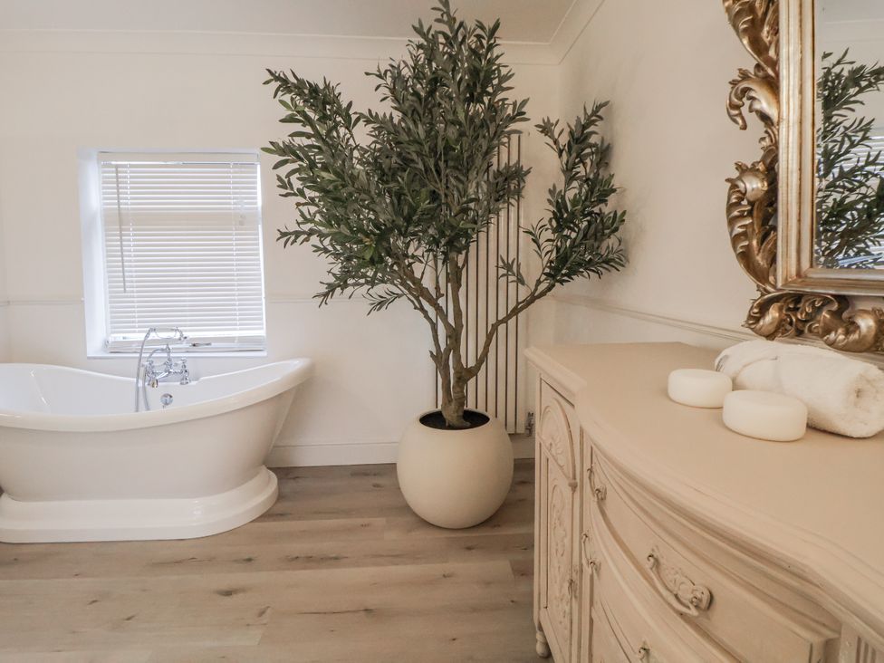 A bathroom with a bathtub and a plant at The House at School Farm in Hassall near Haslington