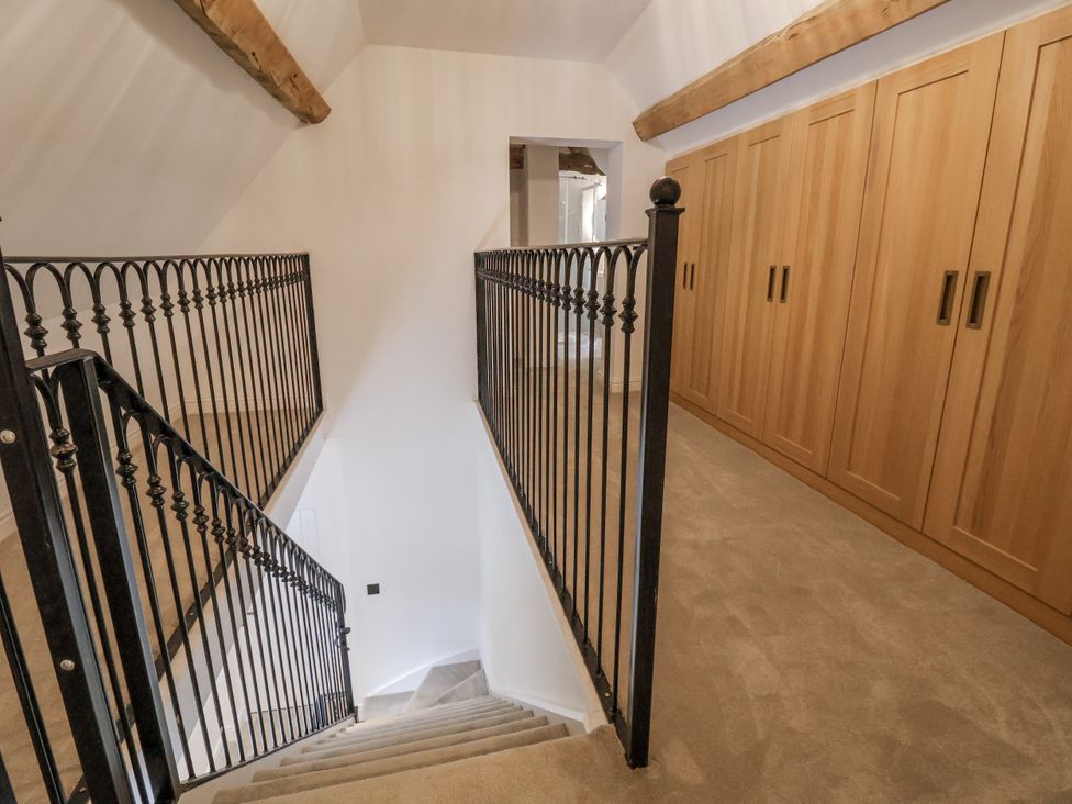 A staircase with railings and wardrobes in a hallway at The House at School Farm Hassall near Haslington