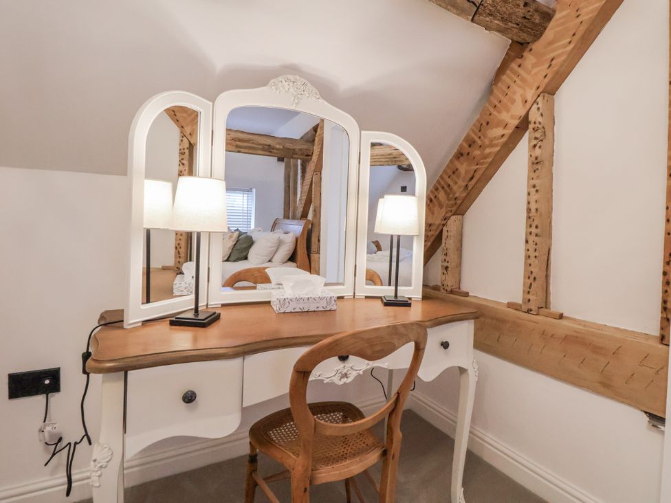 A vanity table with a mirror and chair at The House at School Farm in Hassall near Haslington