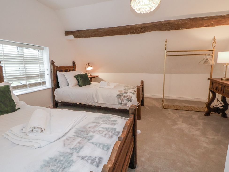 A bedroom with two beds and a clothes rack at The House at School Farm in Hassall near Haslington