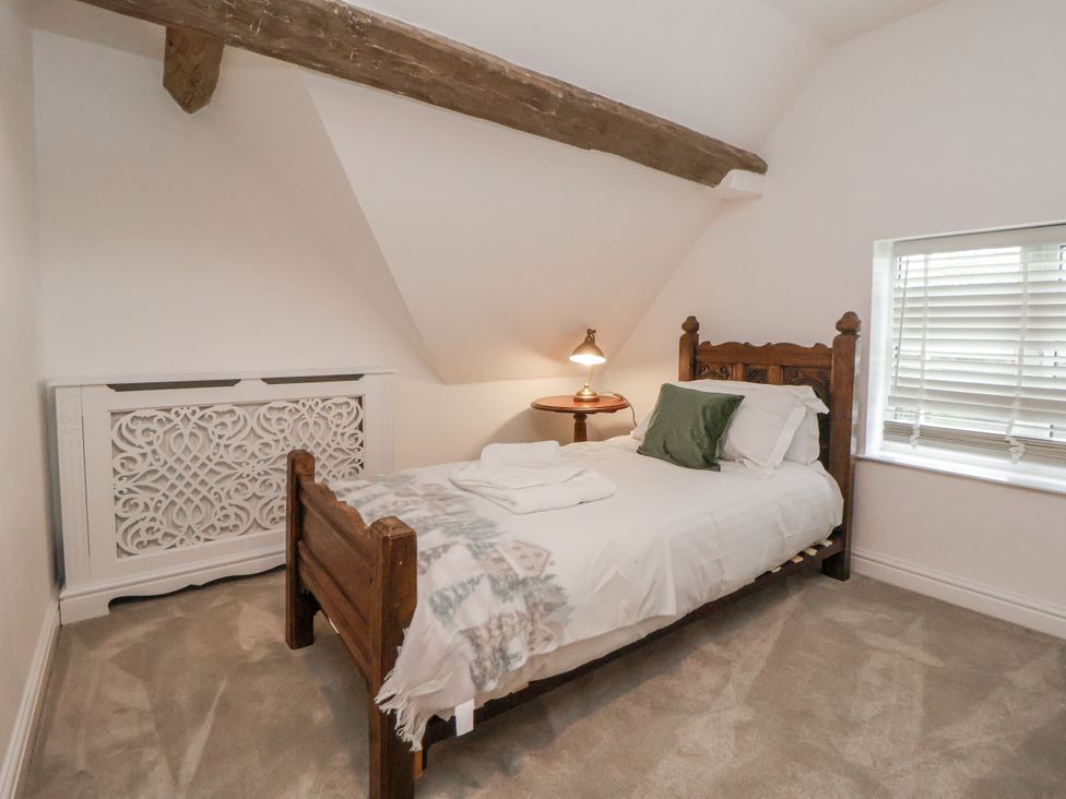 A bedroom with a wooden bed and bedside table at The House at School Farm in Hassall near Haslington