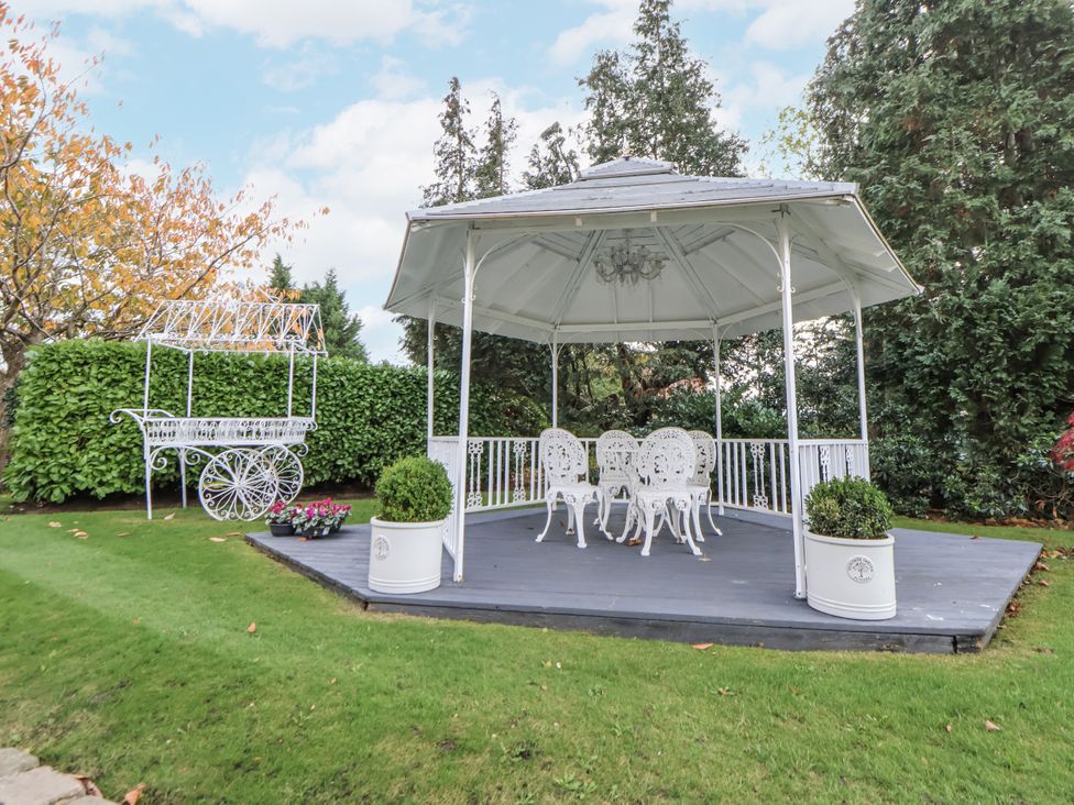 A garden gazebo with chairs and a flower cart at The House at School Farm in Hassall near Haslington