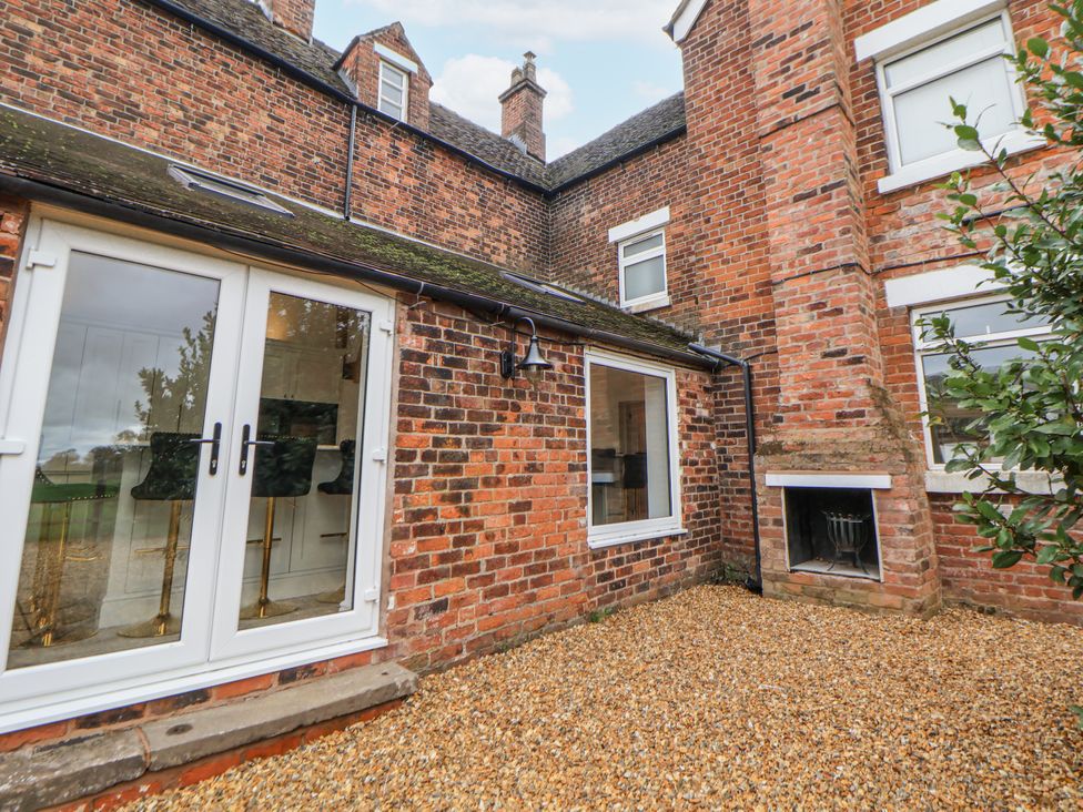 An outdoor area with gravel and brick walls at The House at School Farm in Hassall near Haslington