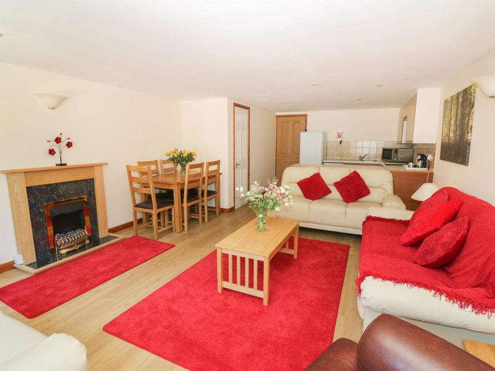 A living room with a fireplace and dining area at Heron Cottage