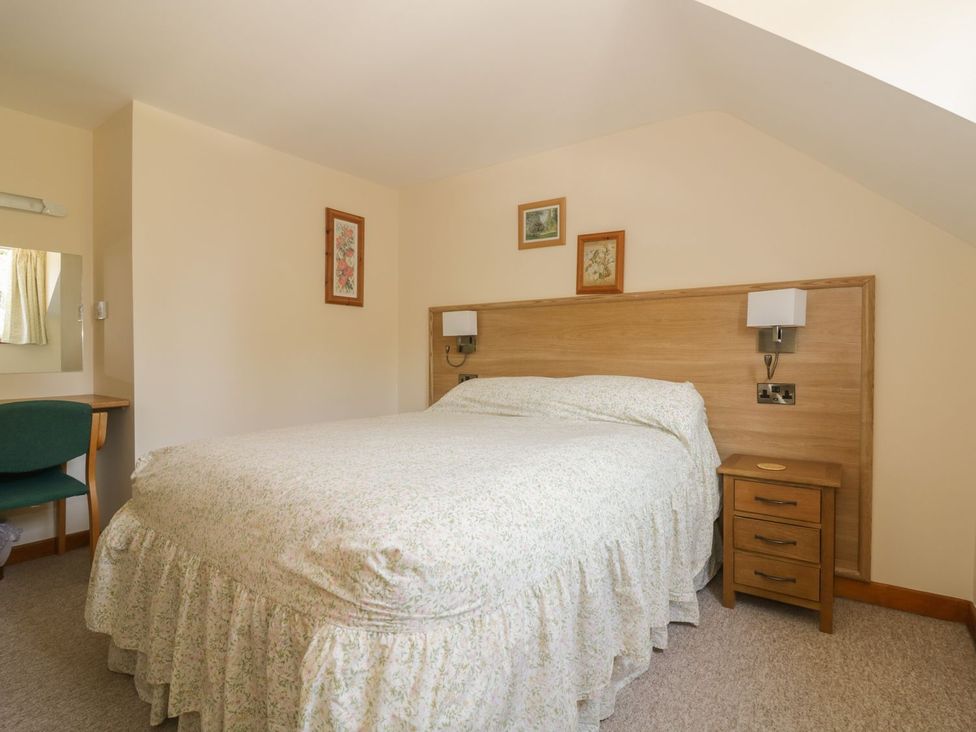 A bedroom with a bed and bedside table at Heron Cottage