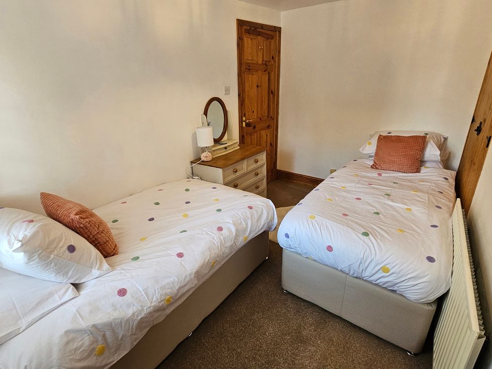A bedroom with two twin beds and a mirror at Twisted Chimney View in Alford