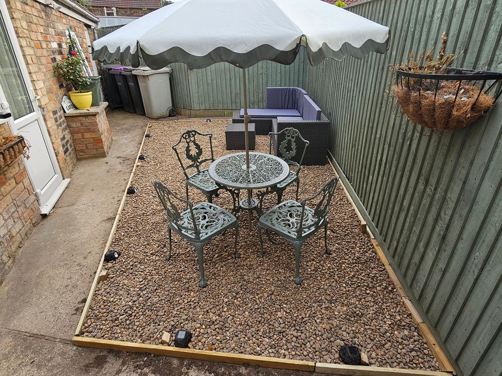 A garden with a table and chairs under an umbrella at Twisted Chimney View in Alford