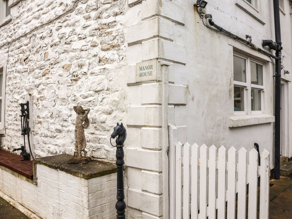 An entrance area with a stone wall and a sign at Manor Farmhouse in Reighton near Filey