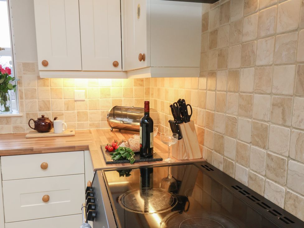 A kitchen with a wine bottle and cutting board at Manor Farmhouse Reighton near Filey