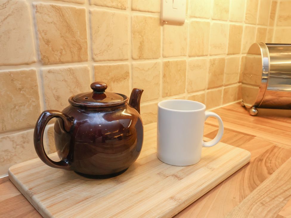 A teapot and a mug on a wooden chopping board in a kitchen at Manor Farmhouse in Reighton near Filey