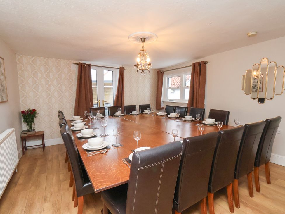 A dining room with a long table set for guests at Manor Farmhouse in Reighton near Filey