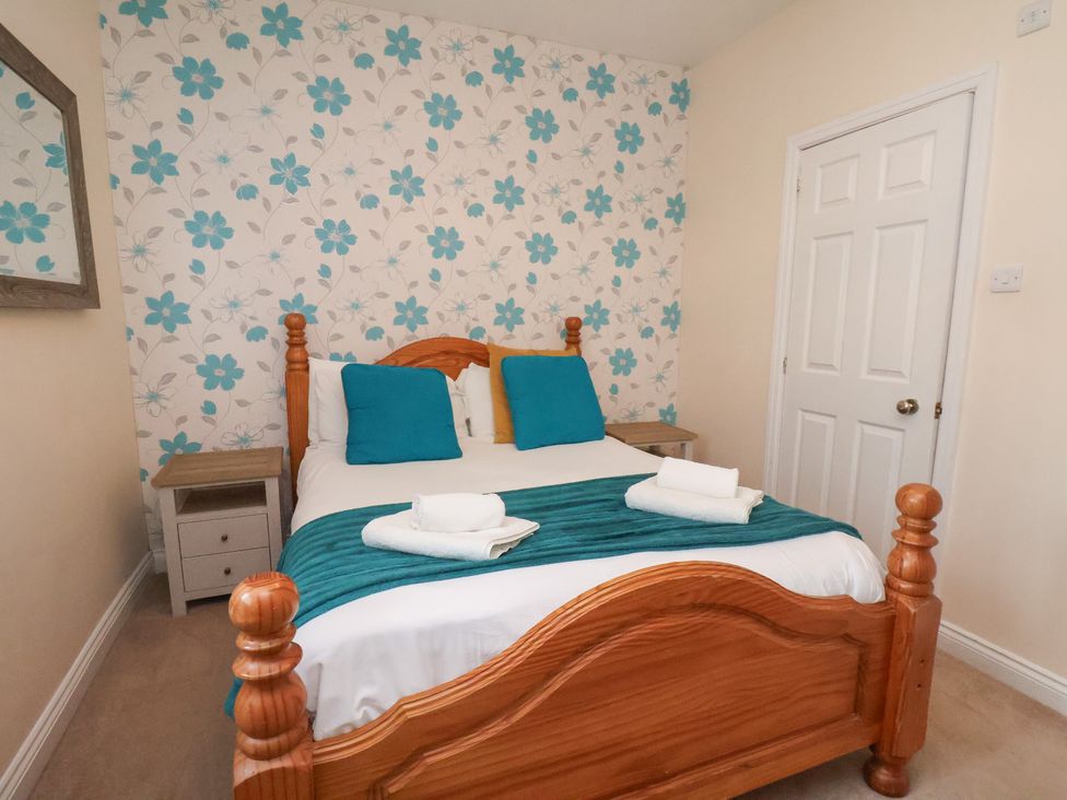 A bedroom with a wooden bed and blue pillows at Manor Farmhouse Reighton near Filey