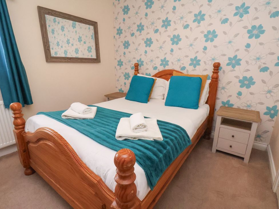 A bedroom with a bed and mirror at Manor Farmhouse in Reighton near Filey