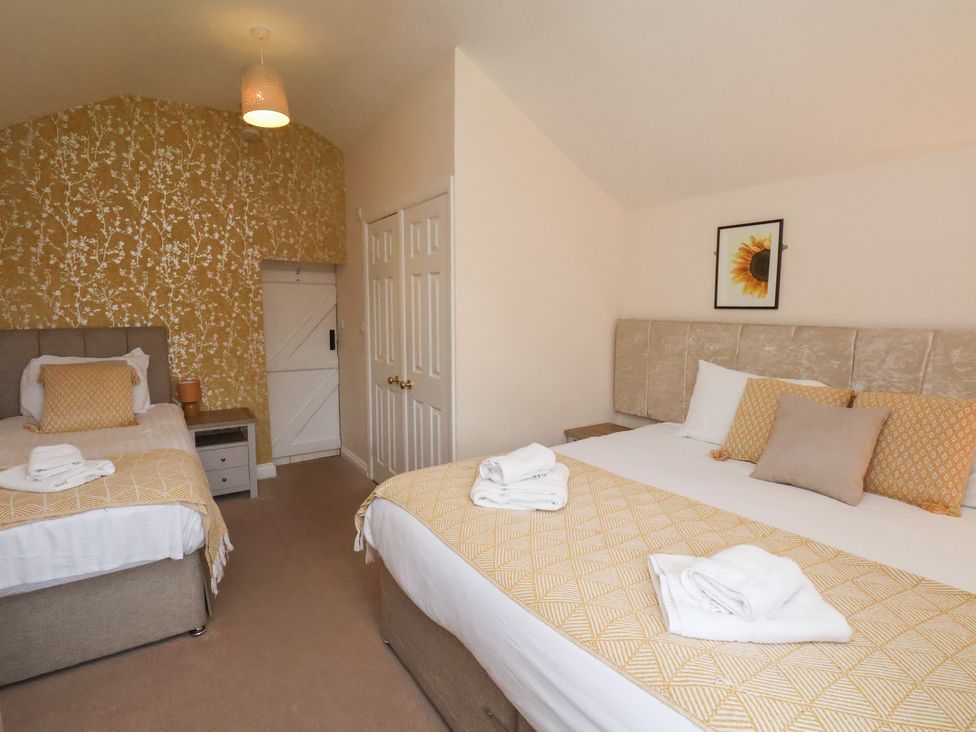 A bedroom with two beds and a wardrobe at Manor Farmhouse in Reighton near Filey