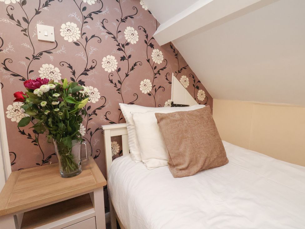 A bedroom with a bed and flowers on a bedside table at Manor Farmhouse in Reighton near Filey