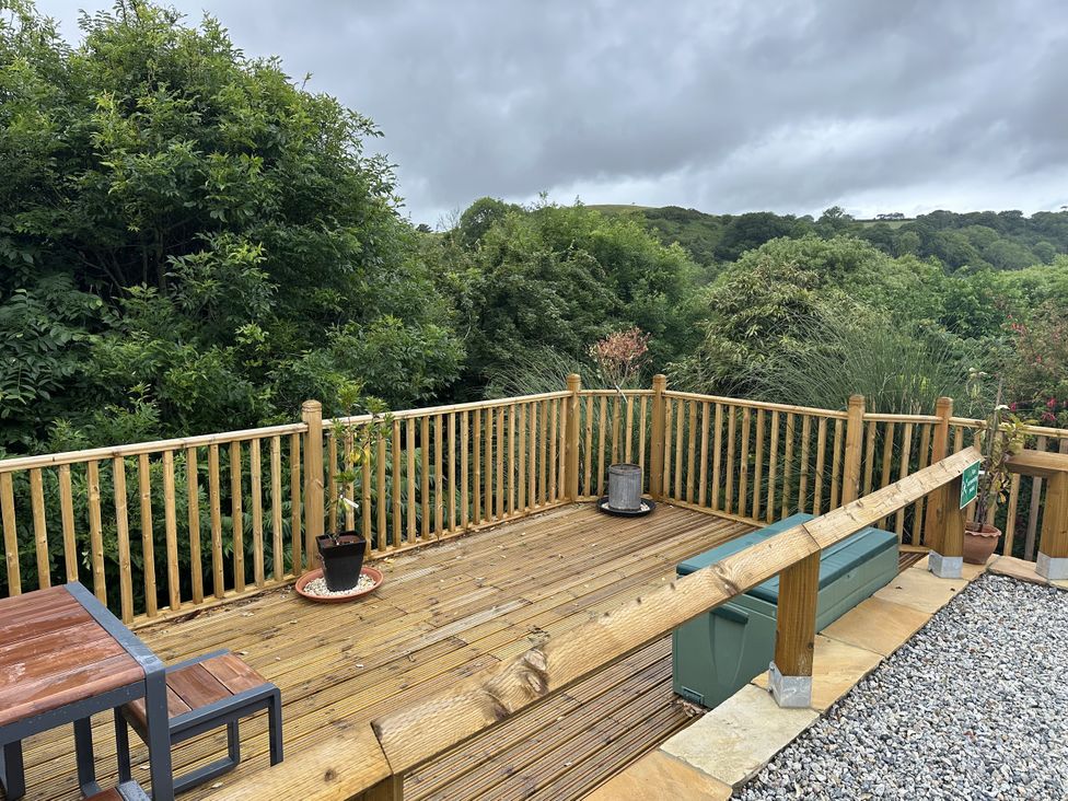 An outdoor deck area with a table, chairs, and plants at Josie in Pentewan