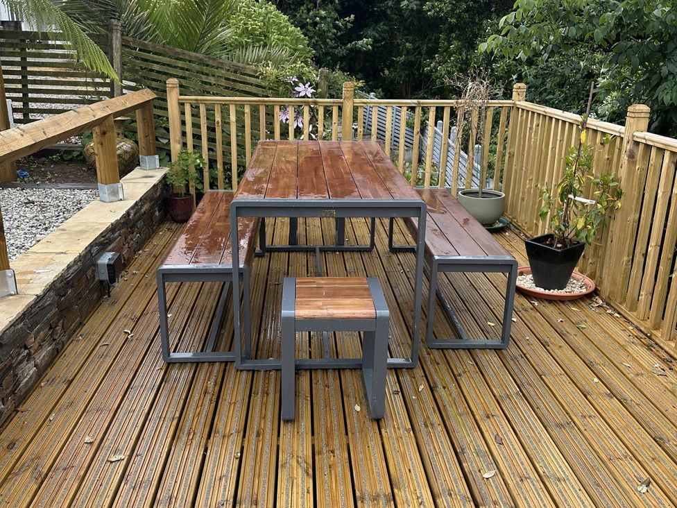 A table and benches on a wooden deck at Josie in Pentewan