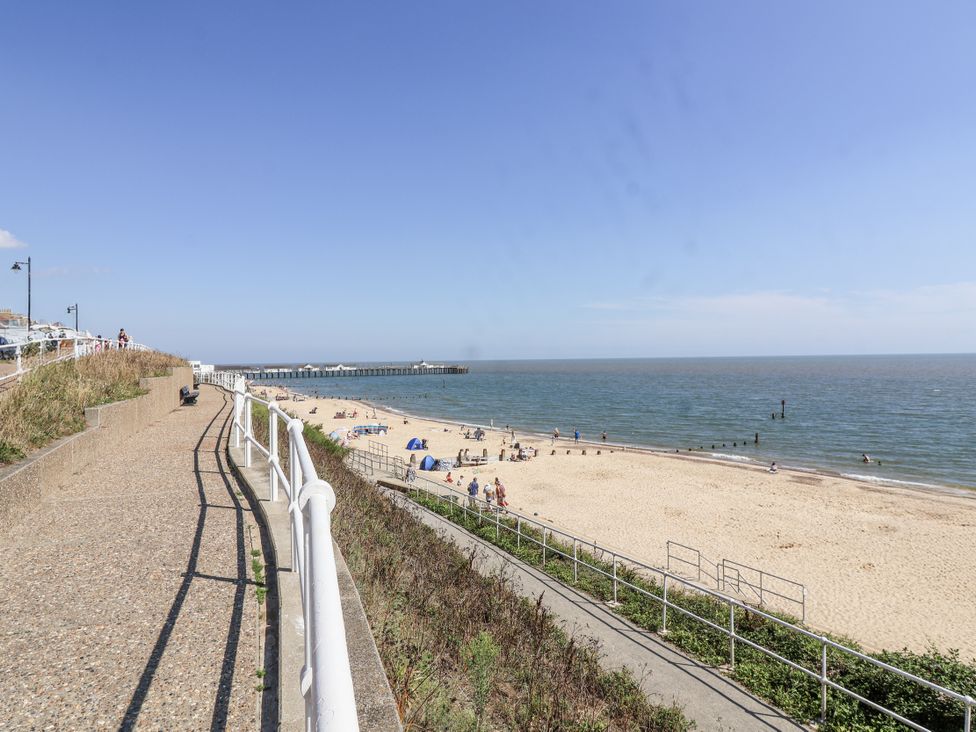 A beach with people enjoying the sun and a pier at 11 The Craighurst Southwold