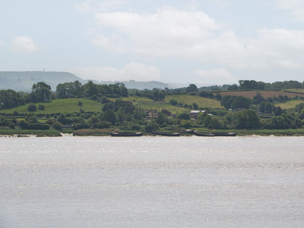 A landscape with hills, water, and boats at Anvil Cottage in Gatcombe near Blakeney