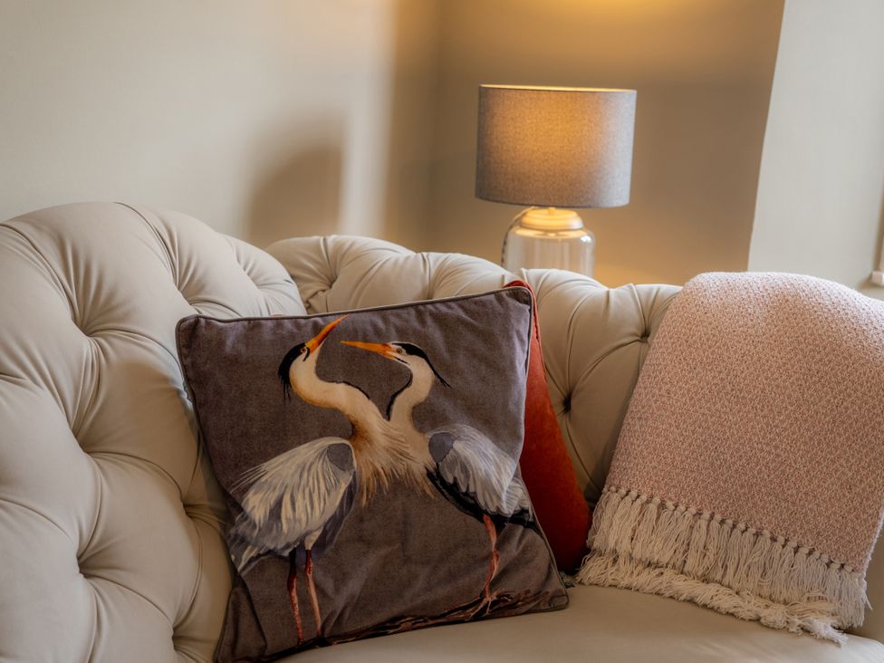 A living room with a cushion featuring herons on a sofa at The George in Whitley Bay