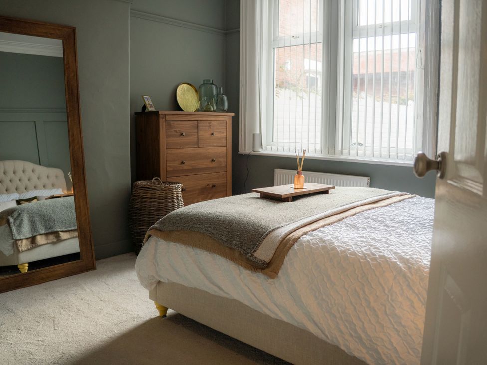 A bedroom with a bed and a dresser at The George in Whitley Bay