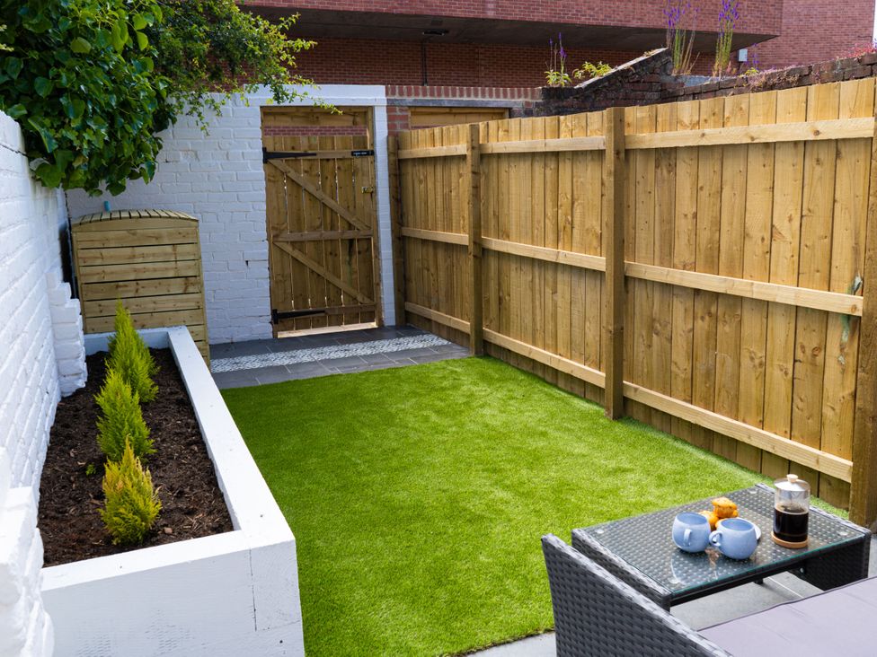 A garden with grass, fence, table and chairs at The George in Whitley Bay