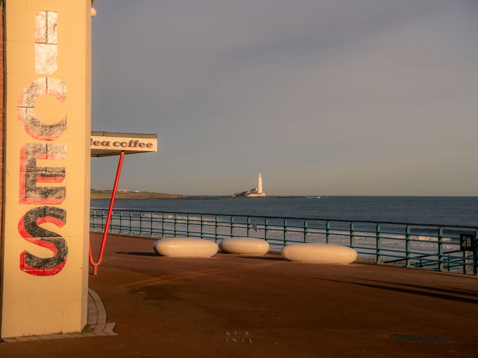 A view of a lighthouse and sea beside a coffee shop sign at The George in Whitley Bay