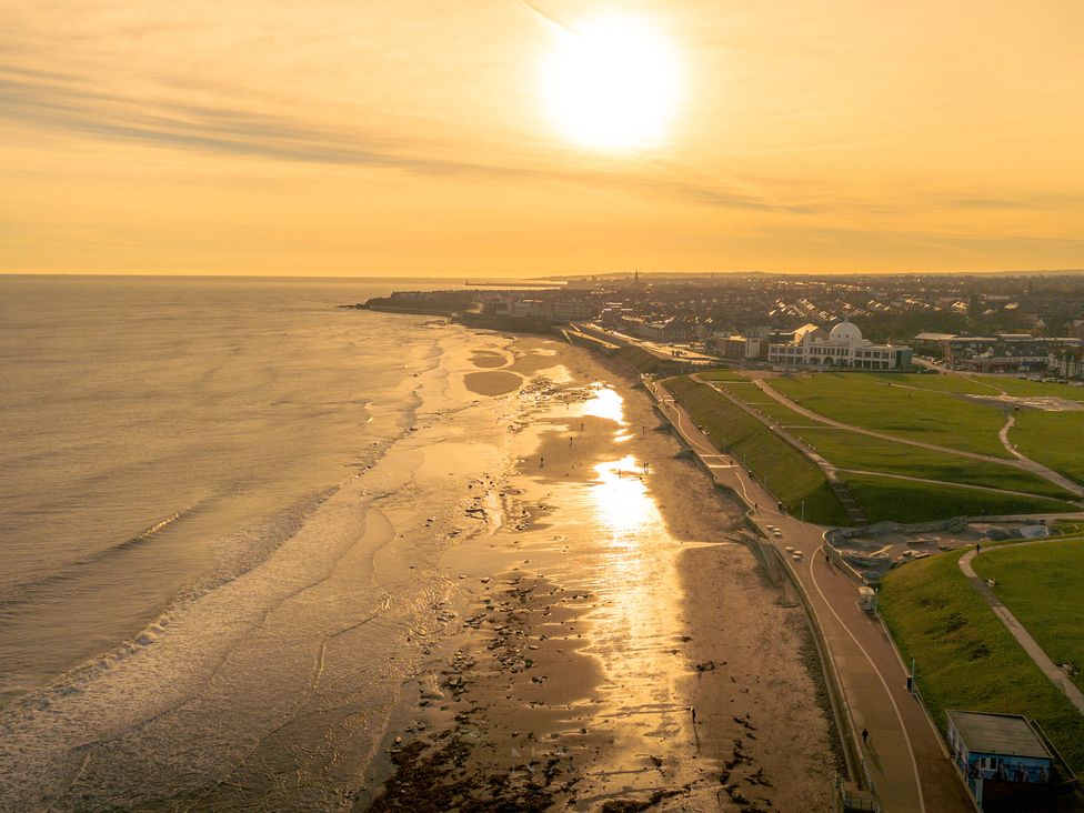 A beach with water and sand under a sunset at The George in Whitley Bay