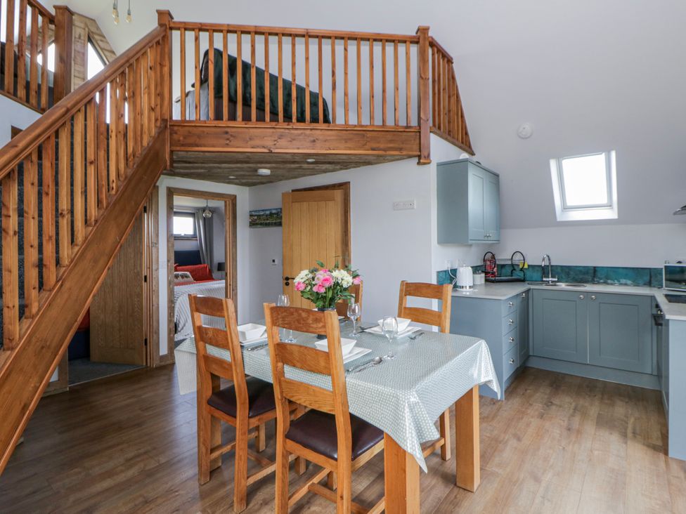 A kitchen with a dining table and staircase at Valley View Hideaway in Ffostrasol