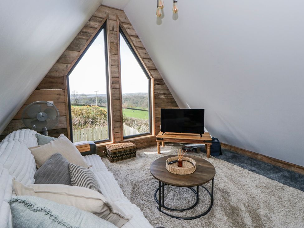 A living room with a television and sofa at Valley View Hideaway in Ffostrasol