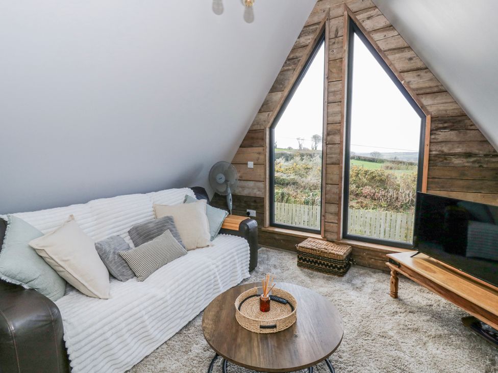 A living room with a sofa and large windows at Valley View Hideaway in Ffostrasol