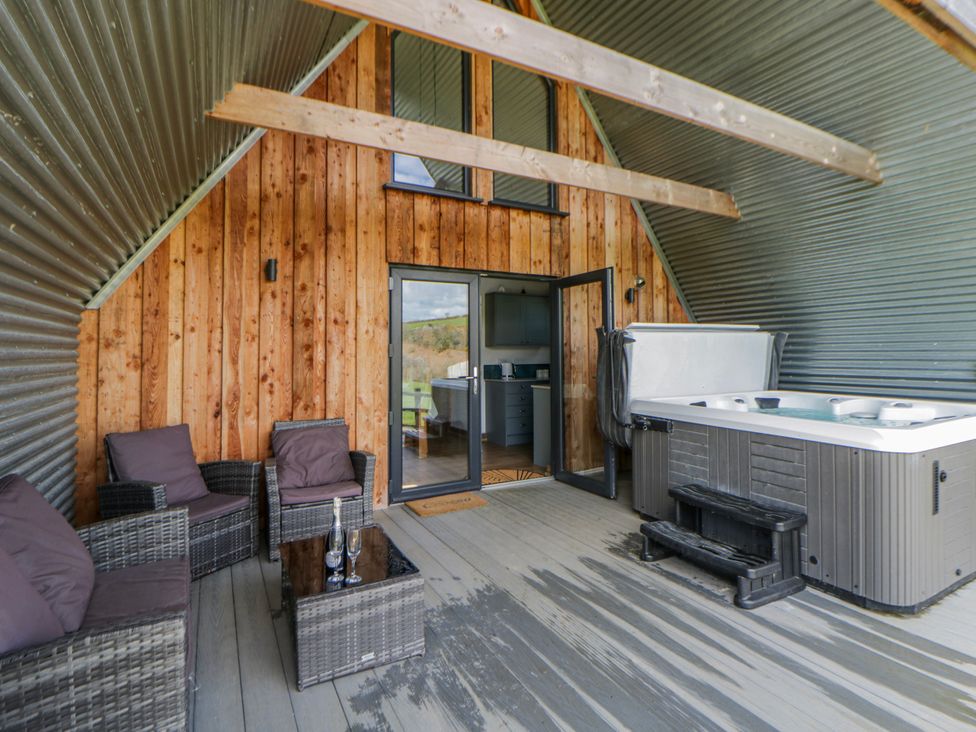 An outdoor seating area with a hot tub at Valley View Hideaway in Ffostrasol