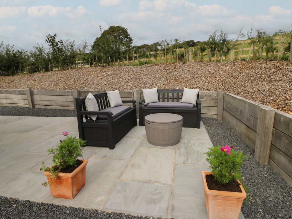 An outdoor seating area with a coffee table and flower pots at Rydlan Aberystwyth