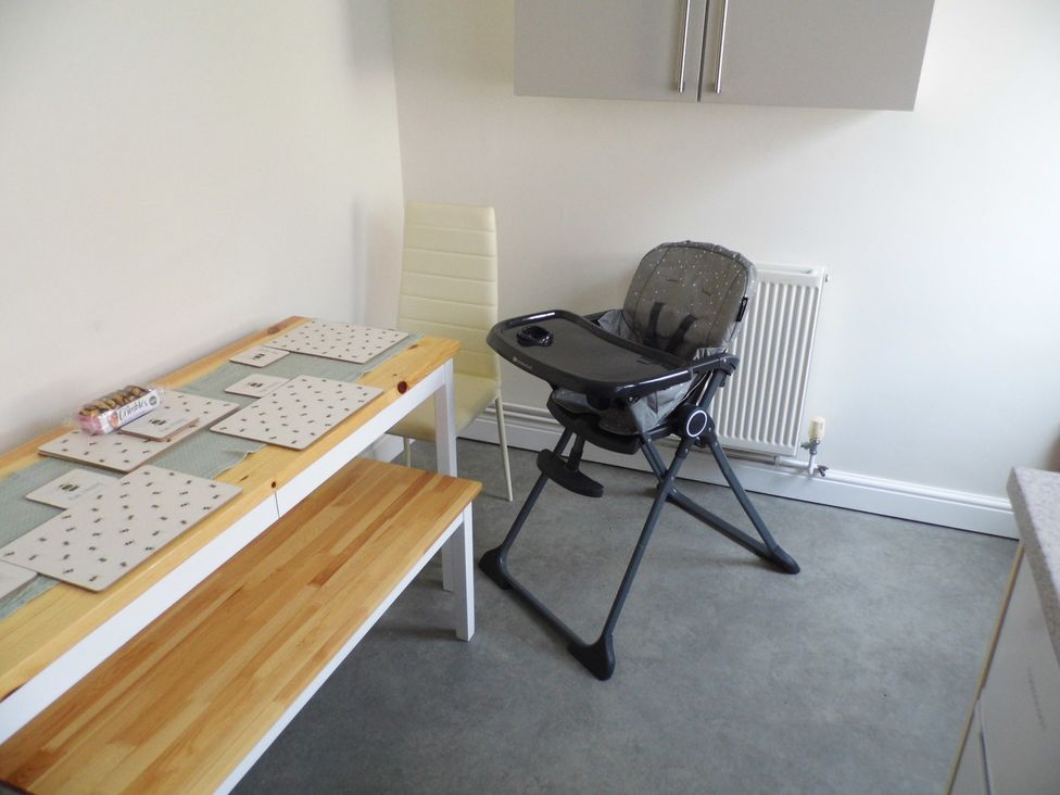 A dining room with a table and high chair at Victoria House in Weymouth