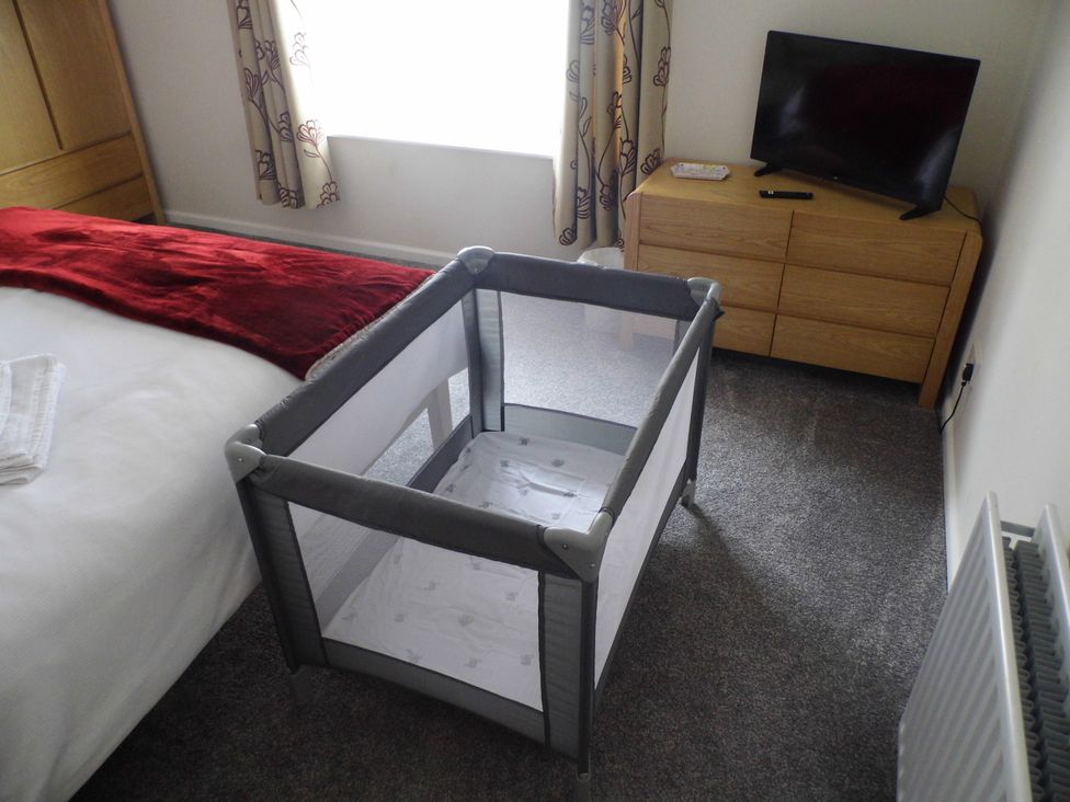 A bedroom with a crib and a television at Victoria House in Weymouth