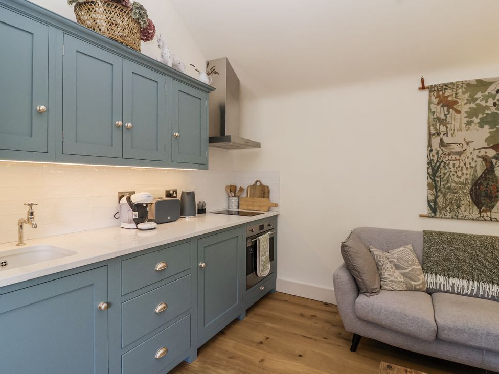 A kitchen with cabinets and a couch at The Little Loft in Burford